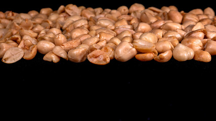 Roasted shelled peanuts with studio lighting appear to float on a black background, perfect for healthy snack illustrations and food designs.