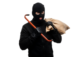 A man in a black hoodie and mask holds a cane, appearing serious as he stands with arms relaxed at his sides.