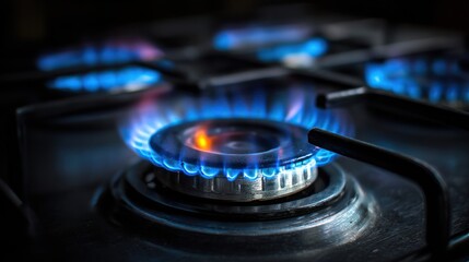 Gas stove burner flames burning blue on a dark stovetop surface.