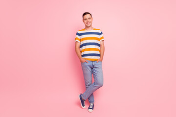 Full length photo of positive young male in trendy pants shirt looking at camera with smile against pink background © Tetiana