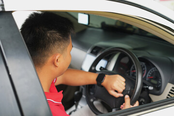 An asian young male driver checks time on watch, online map, stuck in traffic jam and being late...