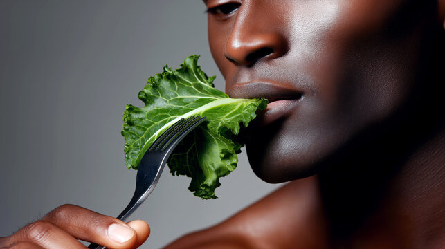 A close-up image capturing a man holding a forkful of fresh leafy greens near his lips