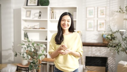 Young entrepreneur looking at camera while standing at home office. Happy female seller staring at camera with confidence while smiling with confidence. Small business or start up concept. Myrmidon.