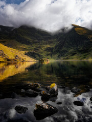 Lough Callee showcases stunning natural beauty with calm waters reflecting dramatic mountains. The landscape captures the essence of Ireland's scenic tranquility under a cloudy sky.