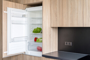Open fridge in a modern kitchen displaying fresh food and organized storage