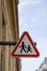 Un panneau triangulaire rouge avertit les conducteurs de la présence de piétons et d'enfants...