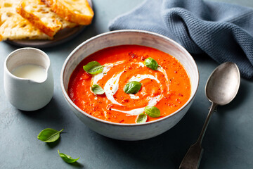 Tomato soup with cream in a white bowl on grey background. Close up.