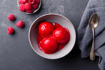 Raspberry ice cream, sorbet, gelato scoops in bowl. Dark grey background. Close up. Top view.