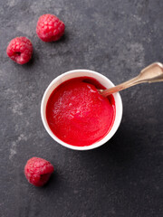 Raspberry sorbet in paper cup. Black stone background. Top view.