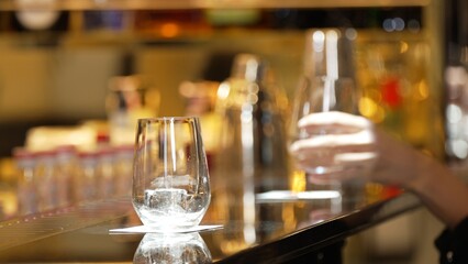Closeup customer hand with gin fizz or tonic soda at luxurious bar side view in atmosphere at bokeh lighting warm nightclub. Lifestyle at night with friends or couple at pub and restaurant. Vinosity.
