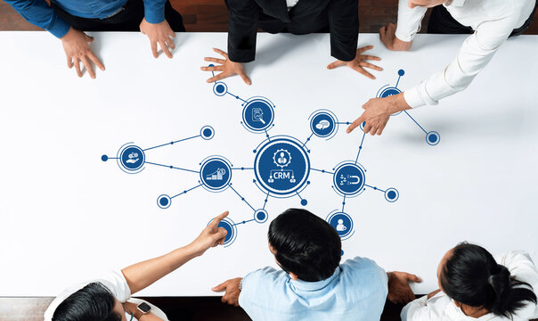 A diverse group of professionals collaborates on a CRM system during a meeting in a modern workspace. They engage in strategic planning and data visualization to enhance business growth. Amity - Powered by Adobe