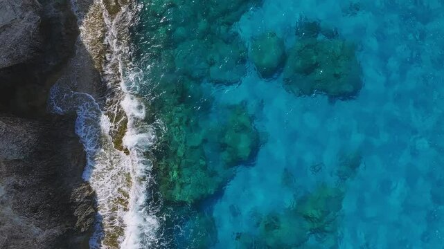 Aerial view of Ayia Napa's coastline in Cyprus, featuring the Love Arch rock formation, turquoise waters, and gentle waves along the rocky shore.