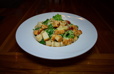 caesar salad with chicken stir on the table