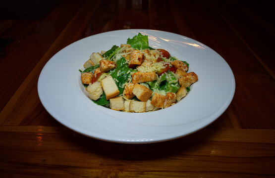 caesar salad with chicken stir on the table