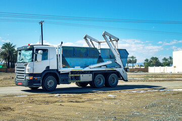 A garbage truck with garbage cans. Oman