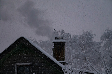 Russian winter in northern olden time hamlet. Snowfall. Smoke is coming from chimney. Frozen...
