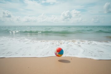 Obraz premium Beach ball on sandy shore the ocean clear sky