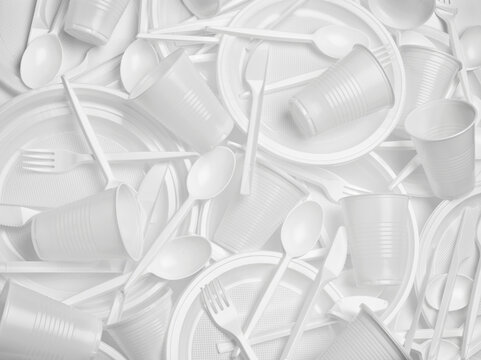 close up of plastic cutlery spoon, fork, knife, plate and cup on white background