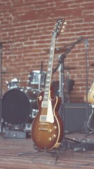 Naklejka premium Guitar Combo Setup in Cozy Music Venue With Brick Wall and Drums in the Background