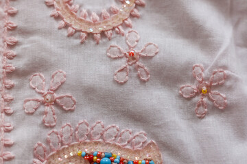 Beautiful embroidery on a pink fabric. Close-up.