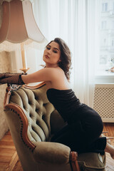 Elegant Woman in Black Gown by the Window with Classic Armchair