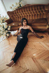 Woman in Black Dress Sitting on Wooden Floor Near Sofa