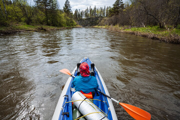 The adventurous kayaker is paddling through the serene waters, completely surrounded by the beauty...