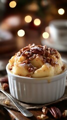 Warm dessert topped with caramel and pecans served in a white dish on a rustic table surrounded by festive lights