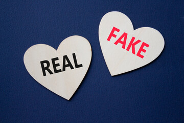Real or Fake symbol. Concept word Real or Fake on wooden hearts. Beautiful deep blue background....