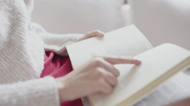 A person engrossed in reading a book, pointing at a passage with their finger