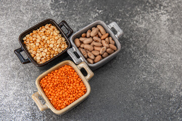 Colorful variety of dried legumes peas, beans, lentils displayed in bowls on a textured surface