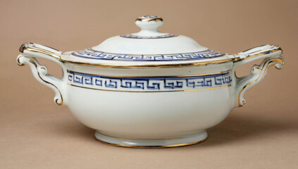 Elegant porcelain serving dish with intricate blue and gold detailing, featuring ornate handles, displayed against a neutral background, showcasing fine craftsmanship and timeless design