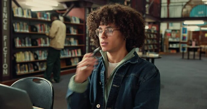 Laptop, thinking and man student with notebook in library studying for university exam with textbooks. Education, computer and male person writing ideas with learning for college test on campus.