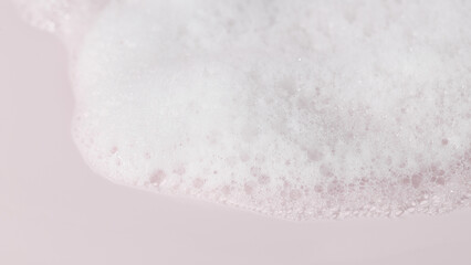 Cosmetic foam smear on pastel pink background, minimal beauty texture