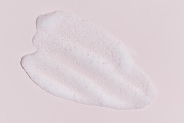 Cosmetic foam smear on pastel pink background, minimal beauty texture
