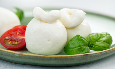 Burrata cheese, Plate of tasty Burrata soft cheese with basil and tomatoes on white background, close up. Italian food. 