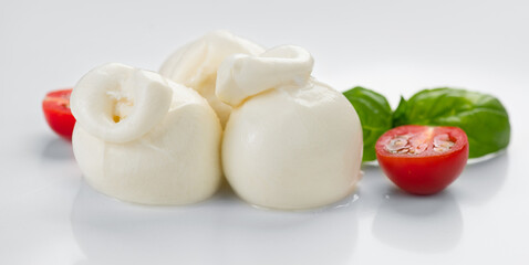 Burrata cheese, tasty Burrata soft cheese with basil leaves and tomatoes on white background, close up. Italian food. 