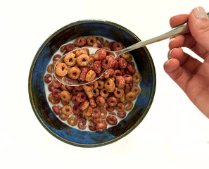 Breakfast ideas - a bowl of colorful cereal with a hand holding a spoonful 