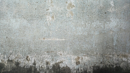 Fototapeta premium The old gray cement wall is stained, peeled and has a peeling surface. The wall has been stained with black stains over time. Walls of ancient buildings. Texture and background image.