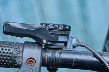 part of bicycle handlebar with black plastic gear shifter and wire on street