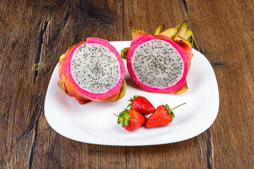 Dragon fruit or pitahaya and strawberries on a white plate.