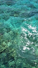 Clear turquoise water with gentle waves and sunlight reflecting on the surface, showcasing vibrant underwater textures and natural beauty in a serene aquatic environment