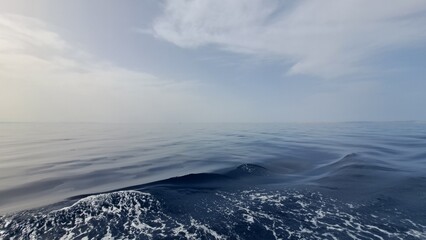 Obraz premium Expansive view of calm ocean waters under a soft blue sky, with gentle waves creating a serene atmosphere, reflecting tranquility and natural beauty in the vast seascape