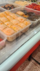 A display of assorted traditional desserts in clear containers. The scene features various sweet treats, showcasing vibrant colors and textures.