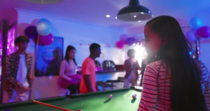 Female shooter approaching pool table in basement striking cue ball celebrating birthday