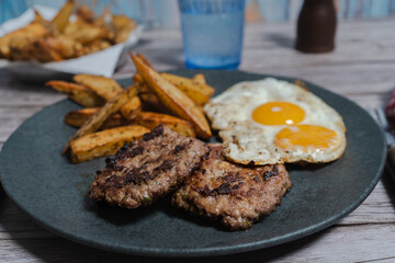 Savoring delicious homemade hamburgers topped with fried eggs and served with crispy potatoes.