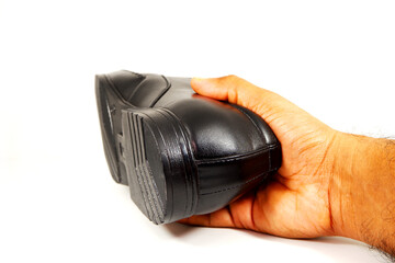 black shoe holding hand with white background close-up shot 