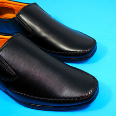 formal black shoes closeup shot on blue background 