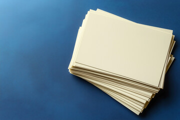 A stack of clean, cream-colored paper sheets, arranged on a vibrant blue surface, from above.