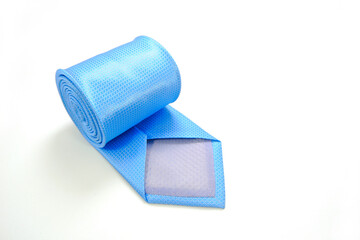 A blue tie rolled on white background closeup shot 